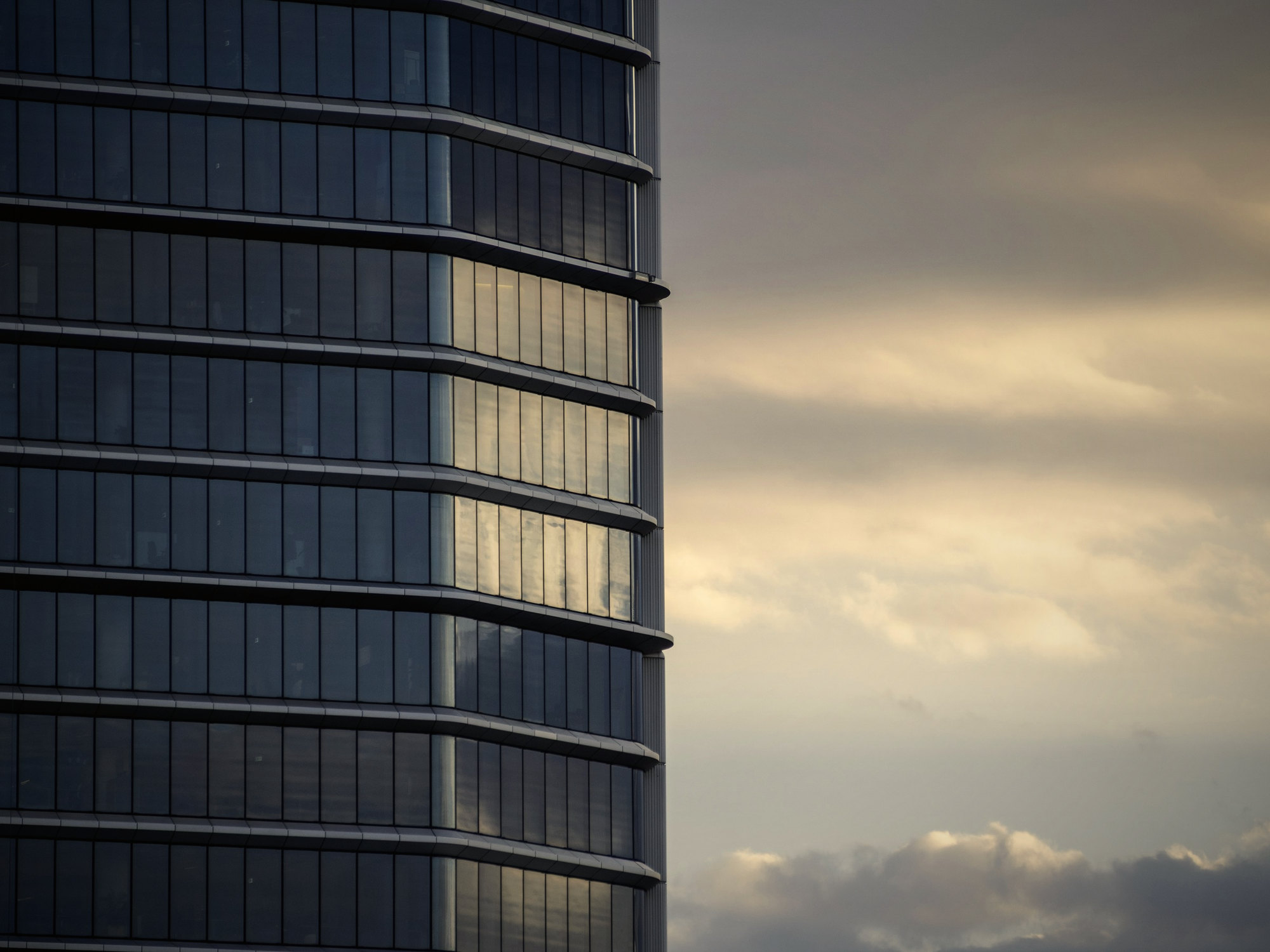 A glass office tower against an evening sky