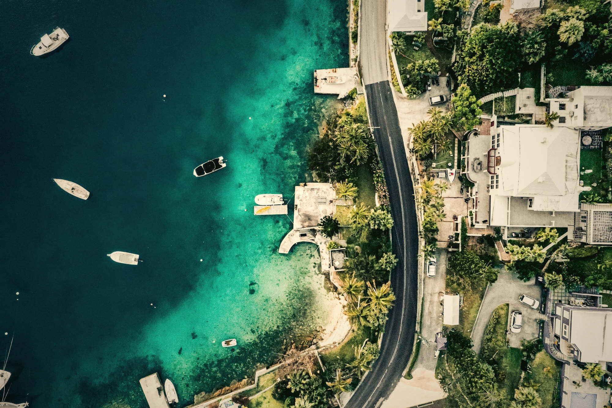 Boats on turquoise water along a coastline, from above