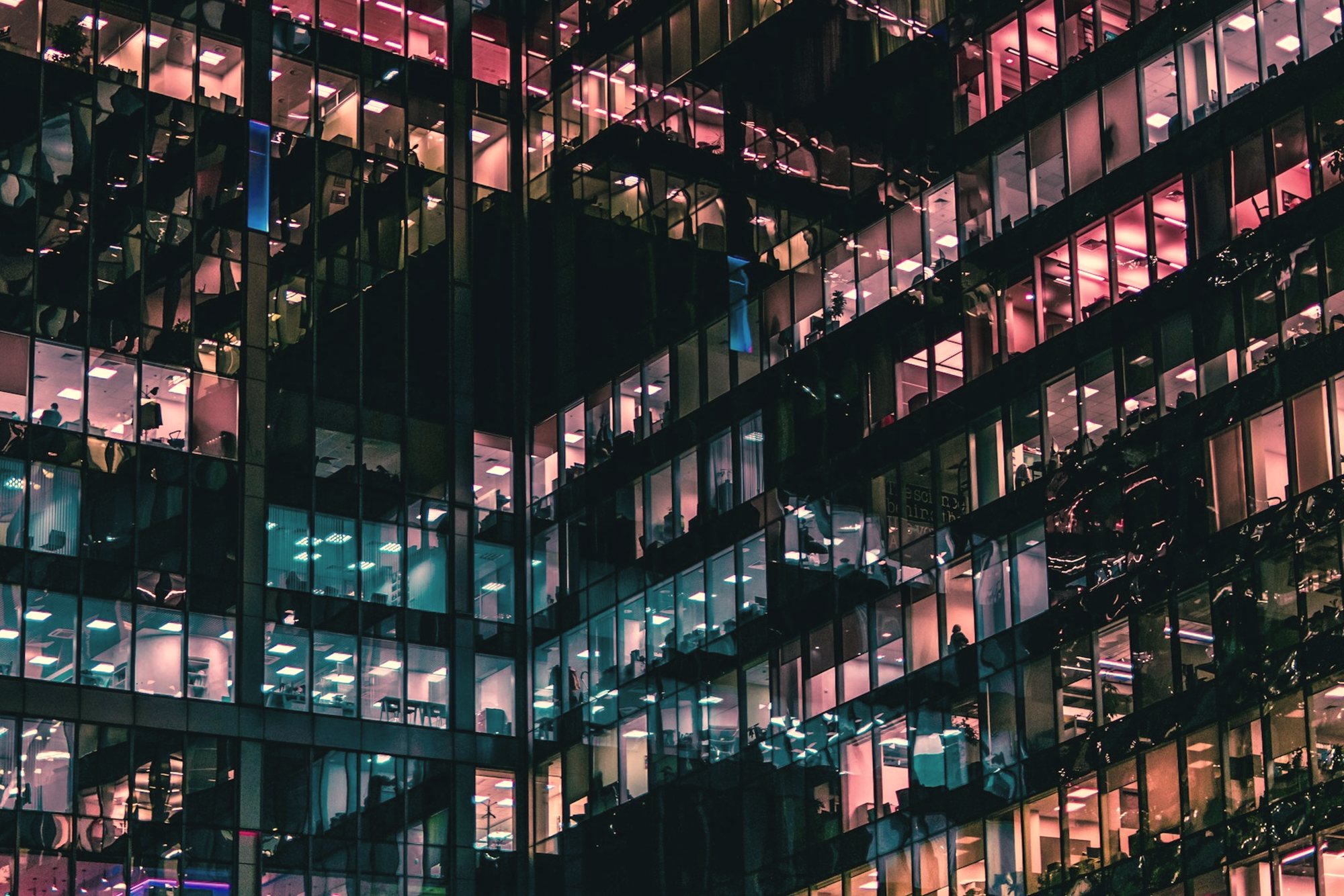 Lit office floors seen through a glass facade at night