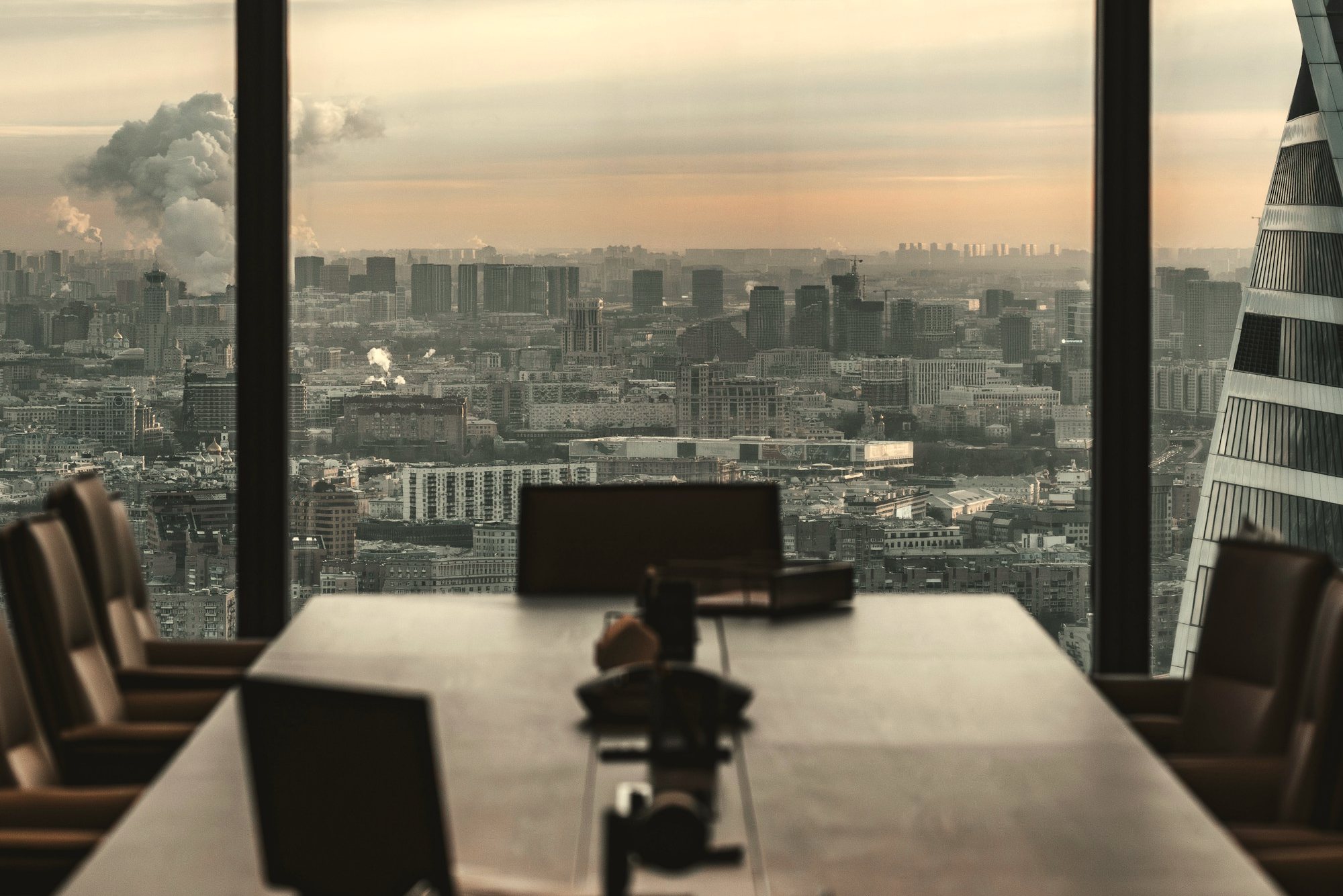 An empty boardroom overlooking a city at dusk