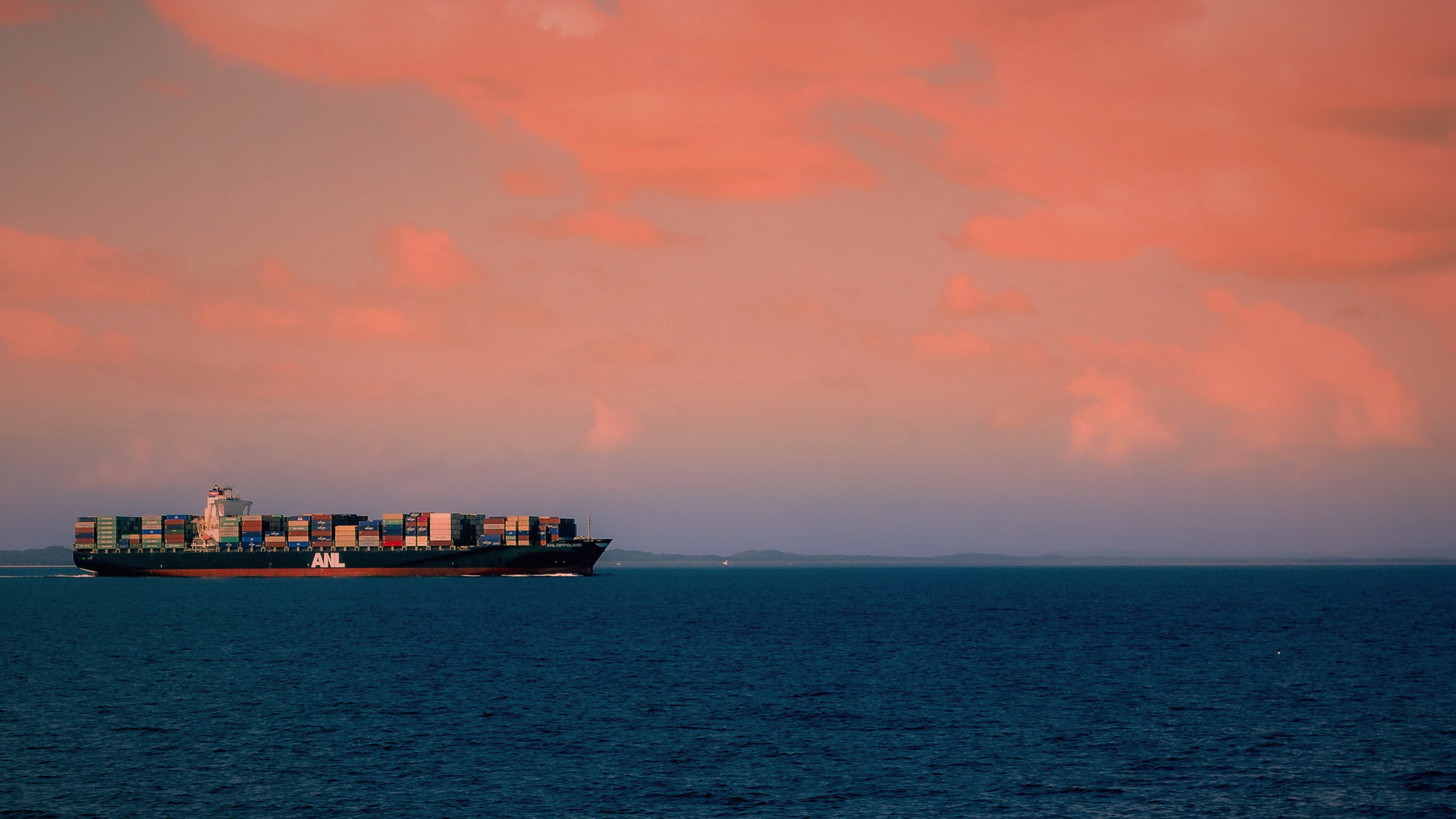 A cargo ship on the horizon at sunset