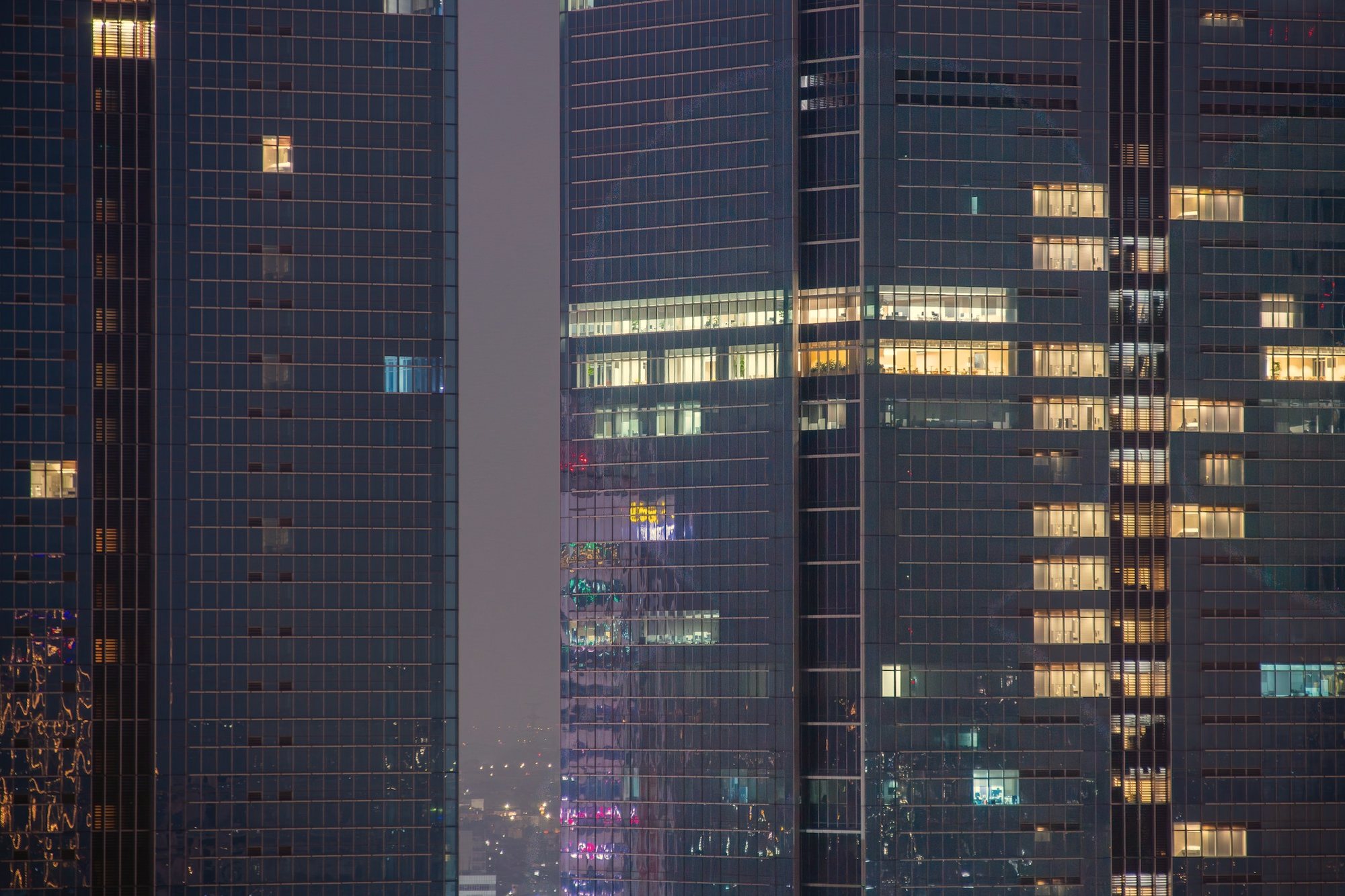 Two glass office towers with lit windows at night